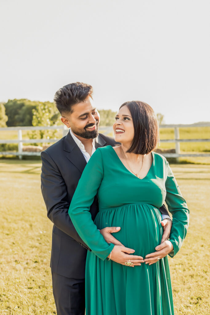 Smiling couple, the woman with a visible baby bump the man gently touching