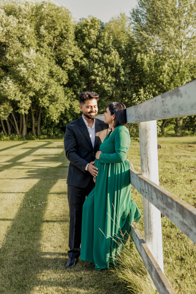 Smiling couple, the woman with a visible baby bump the man gently touching