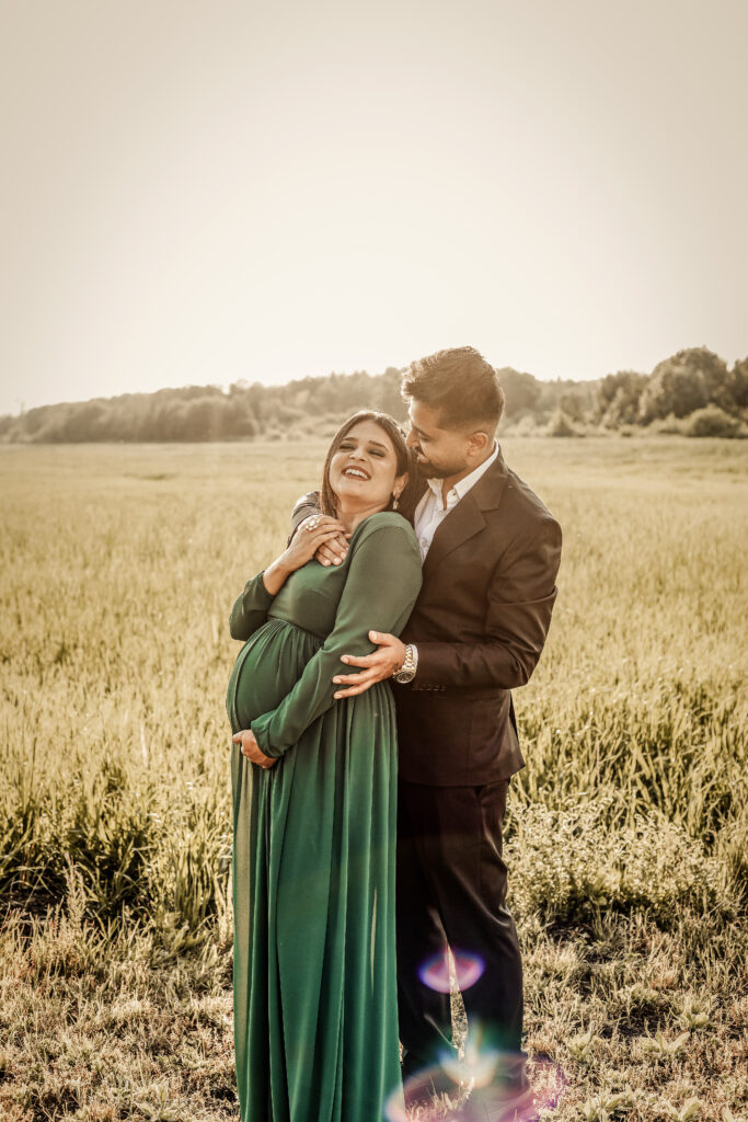 Smiling couple, the woman with a visible baby bump the man gently touching