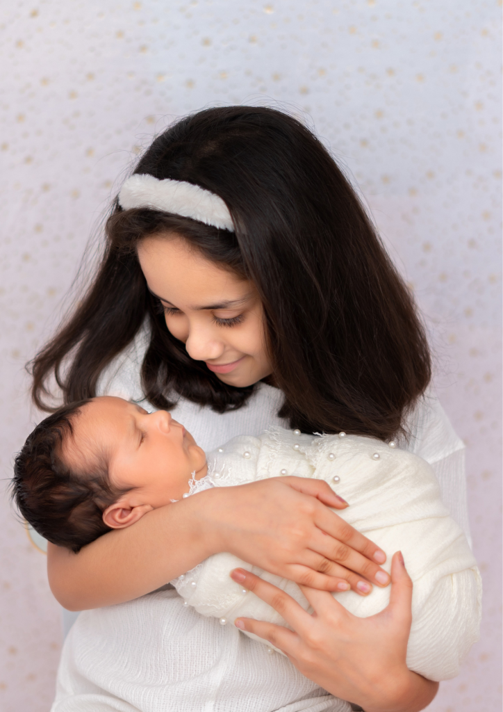 a small girl holding her newborn brother