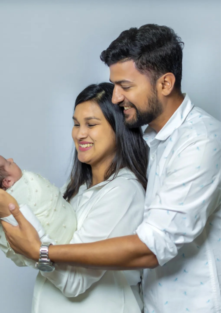 mother and father holding their baby in their hands looking happy