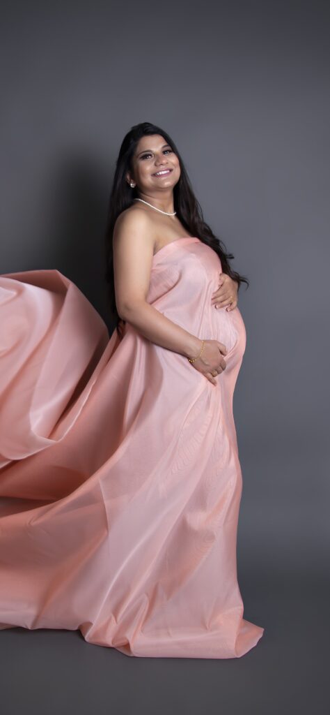 a pregnant women wearing baby pink dress looking happy